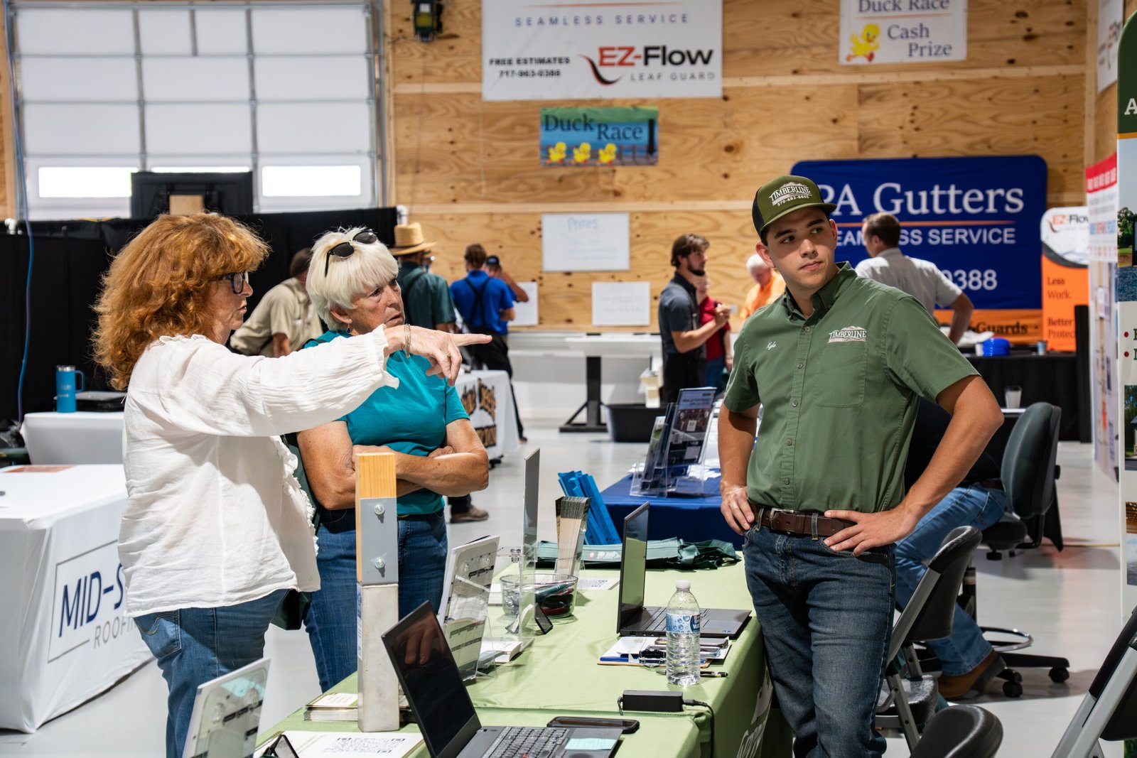 Photograph of a business booth of clients pointing to ask a question.