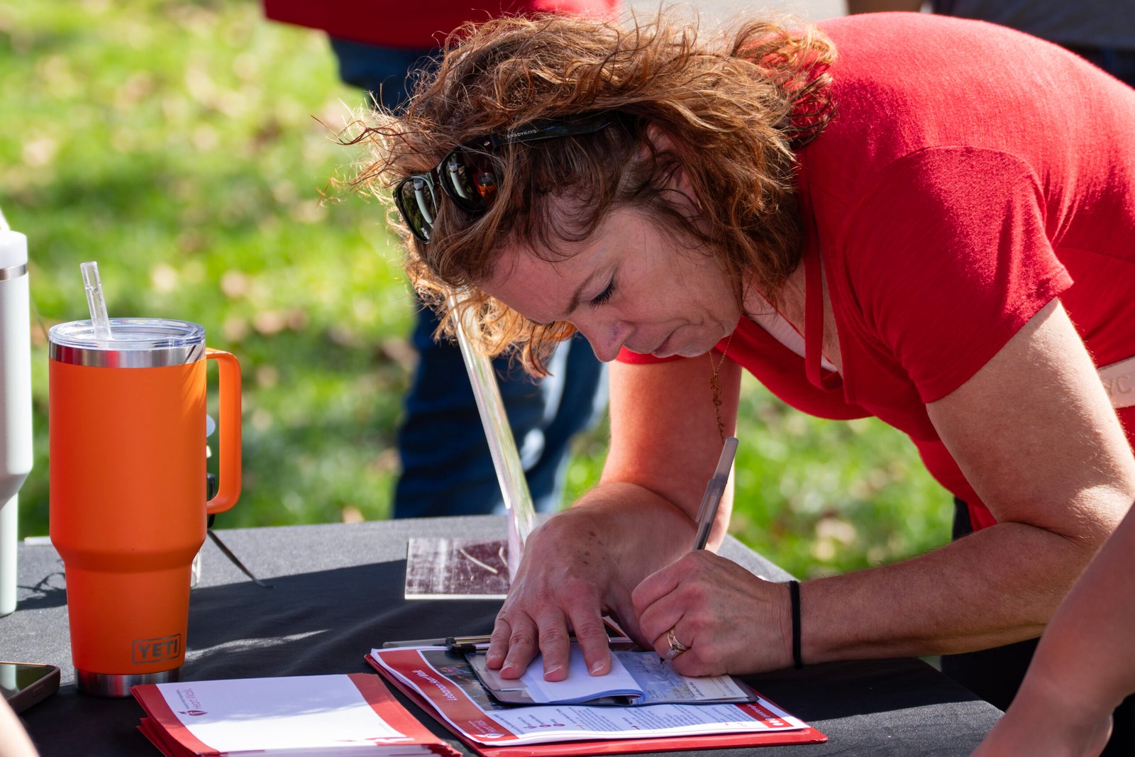 Lady writing in a check book to give a donation to charity event.