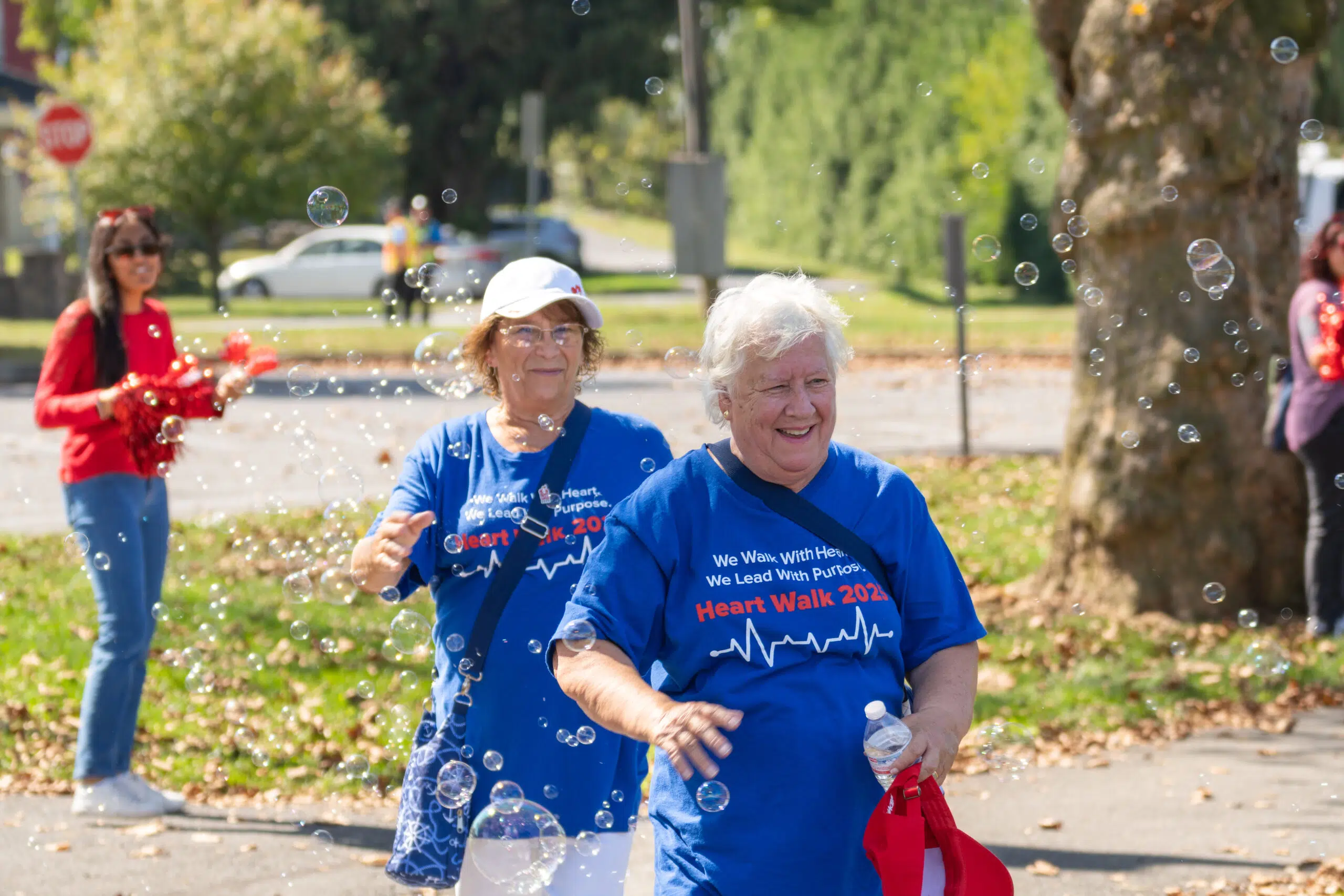 Photograph if two older ladies finishing walking and walking through bubbles.