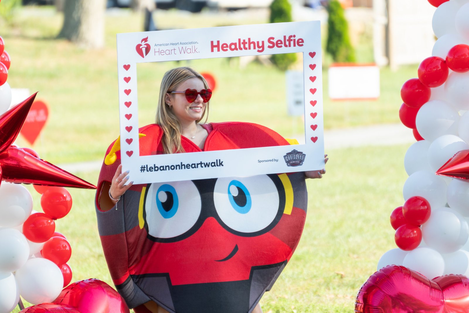 Girl in heart costume holding a healthy selfie sign posing for a photograph.