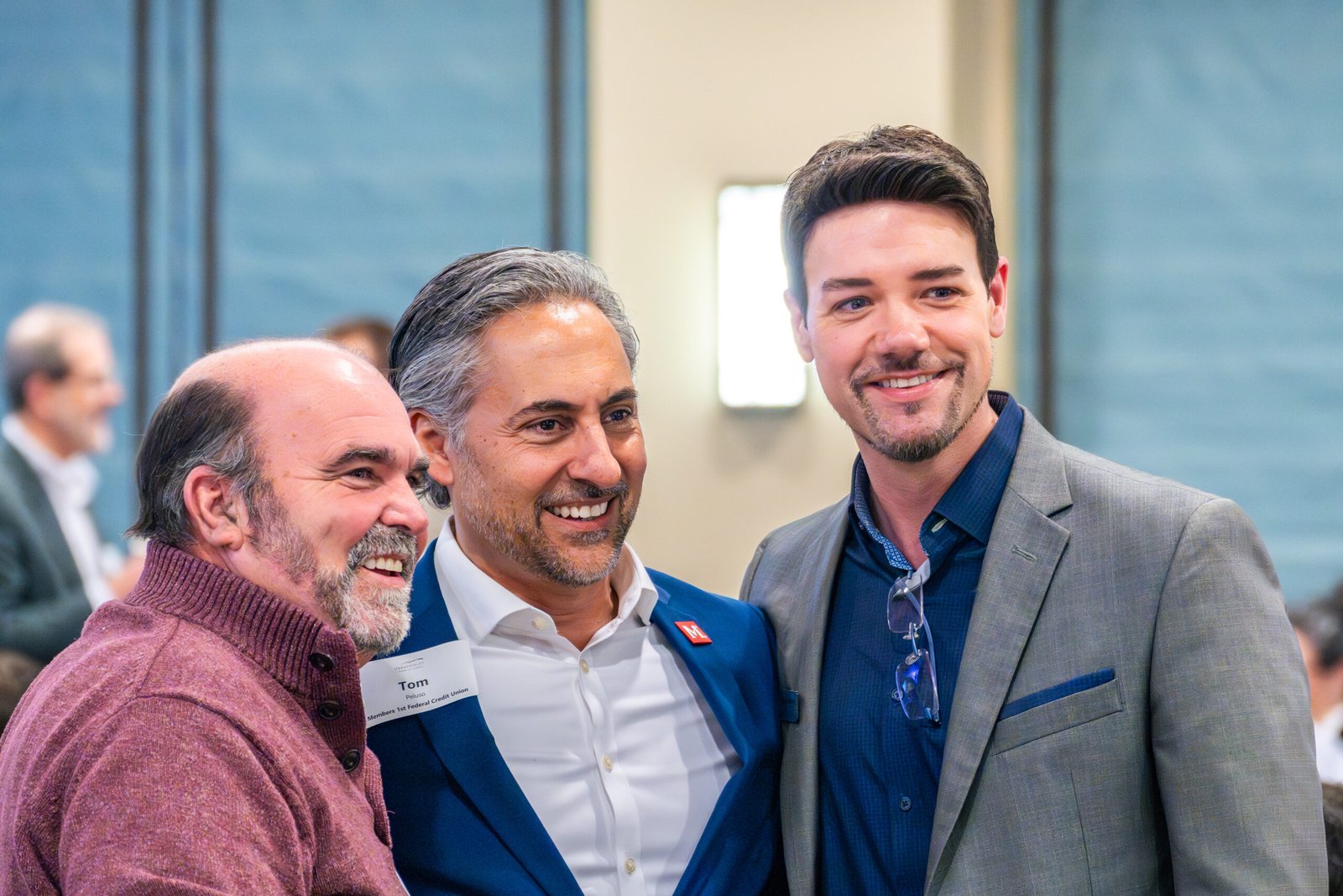 3 guys huddled together taking a picture at an event