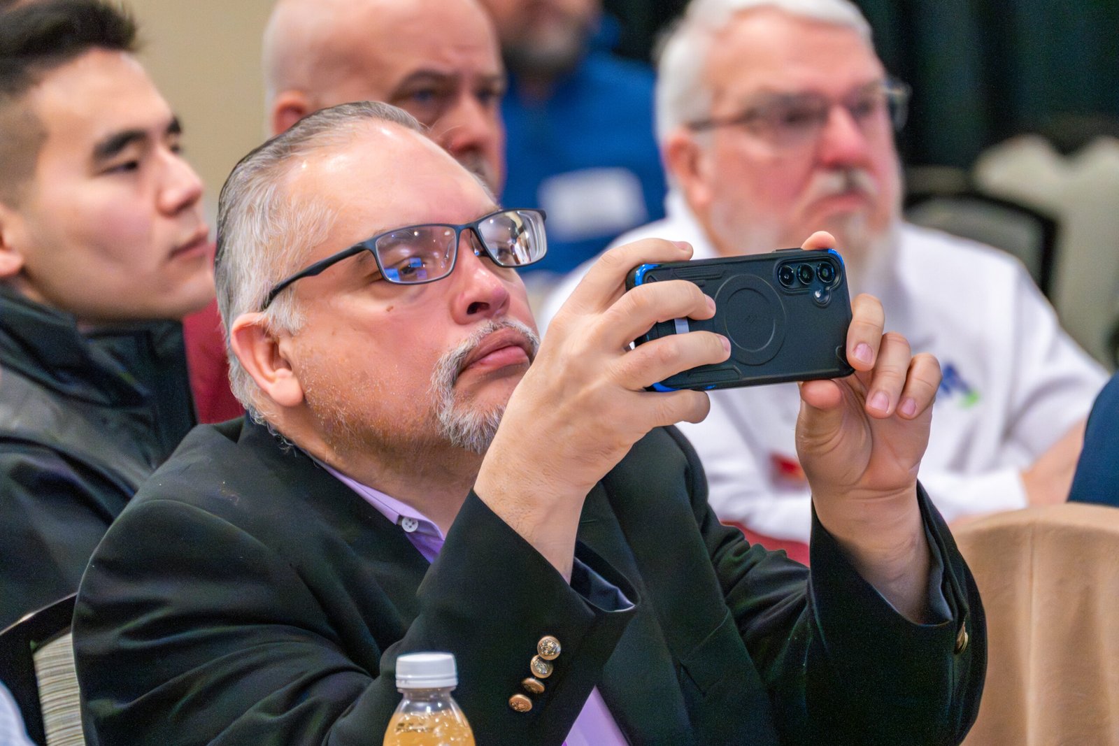 guy holds up phone to take a picture of a conference event