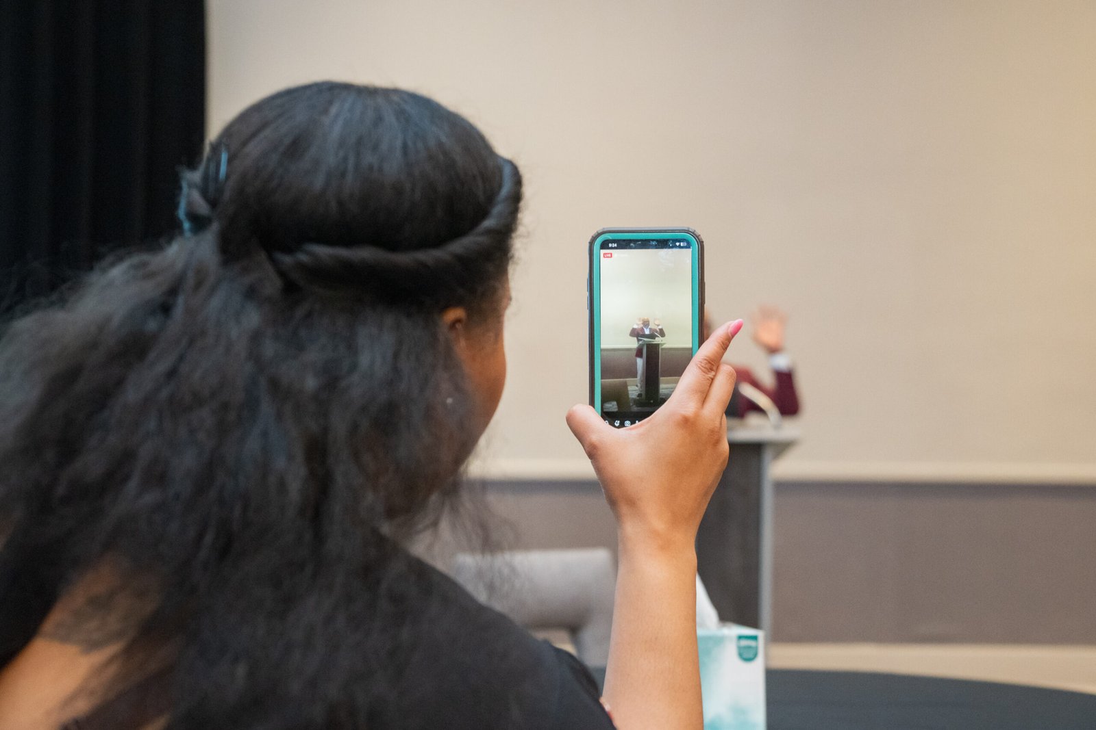 Atendee recording the conference speaker on her phone